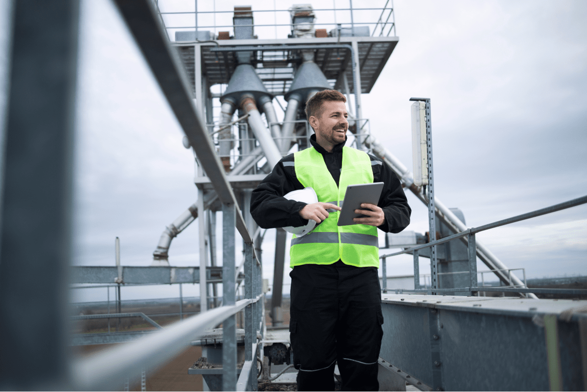An engineer using a digital tablet to monitor operations at an industrial site, demonstrating the integration of technology in the company's processes.