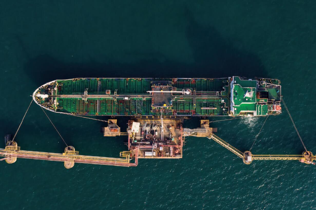 Aerial view of an oil tanker docked at an offshore facility, highlighting the vessel's intricate deck layout and the surrounding docking infrastructure.