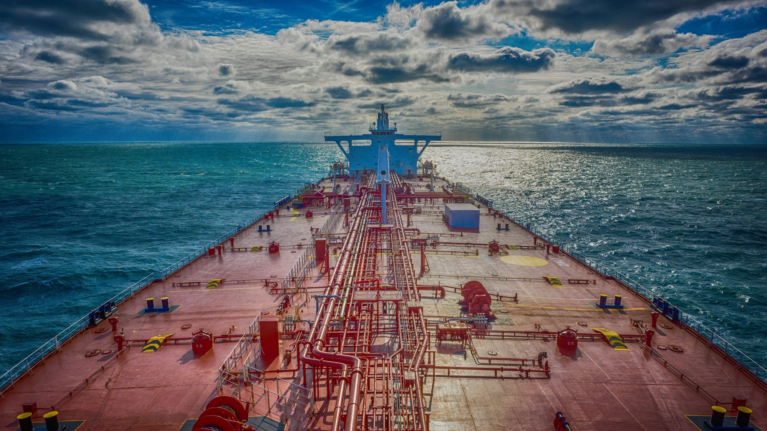 An oil tanker navigating the open sea under a dramatic sky, illustrating the scale and endurance required for maritime oil transport.